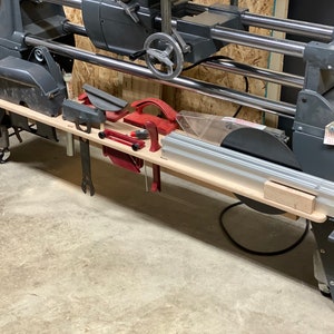 May include: A wooden shelf with various tools and accessories hanging from it. The shelf is attached to a large, gray machine with a black power cord.