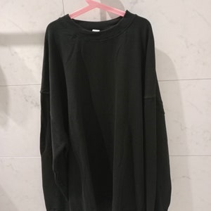 Pu&ograve; includere: Una felpa nera a maniche lunghe con collo rotondo.