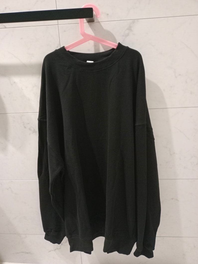 Pu&ograve; includere: Una felpa nera a maniche lunghe con collo rotondo.