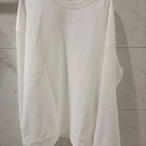 Pu&ograve; includere: Una felpa bianca a maniche lunghe con collo rotondo.