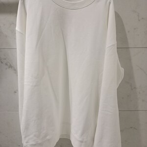 Pu&ograve; includere: Una felpa bianca a maniche lunghe con collo rotondo.