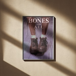 May include: Movie poster for the film "Bones and All", directed by Luca Guadagnino. The poster features a pair of brown leather boots with laces, worn by a person standing on a tiled floor. The title of the film is in large white letters.