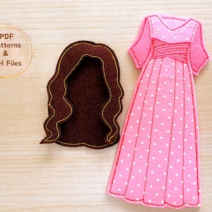 May include: A felt craft pattern for a dress with white polka dots on a pink background and a separate felt pattern for brown hair.