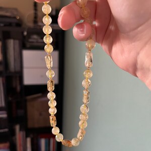 May include: A gold and clear crystal beaded necklace with rectangular beads interspersed throughout.