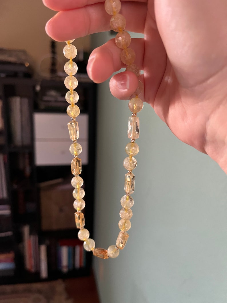 May include: A gold and clear crystal beaded necklace with rectangular beads interspersed throughout.