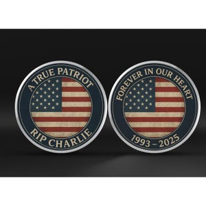 Op de afbeelding: Twee ronde herdenkingsmunten met een ontwerp van de Amerikaanse vlag. E&eacute;n munt leest "A True Patriot RIP Charlie" en de andere "Forever in Our Heart 1993-2025". De munten hebben een blauwe rand en een distressed vlag achtergrond.