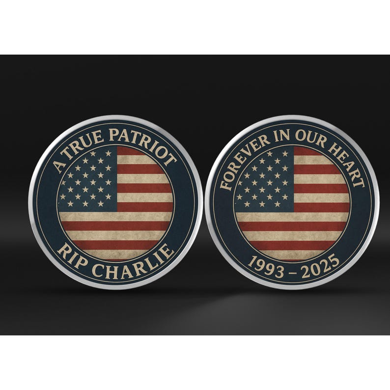 Op de afbeelding: Twee ronde herdenkingsmunten met een ontwerp van de Amerikaanse vlag. E&eacute;n munt leest "A True Patriot RIP Charlie" en de andere "Forever in Our Heart 1993-2025". De munten hebben een blauwe rand en een distressed vlag achtergrond.