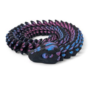 May include: A 3D printed dragon curled up in a circle. The dragon is black with pink and blue accents. The dragon's scales are detailed and textured.