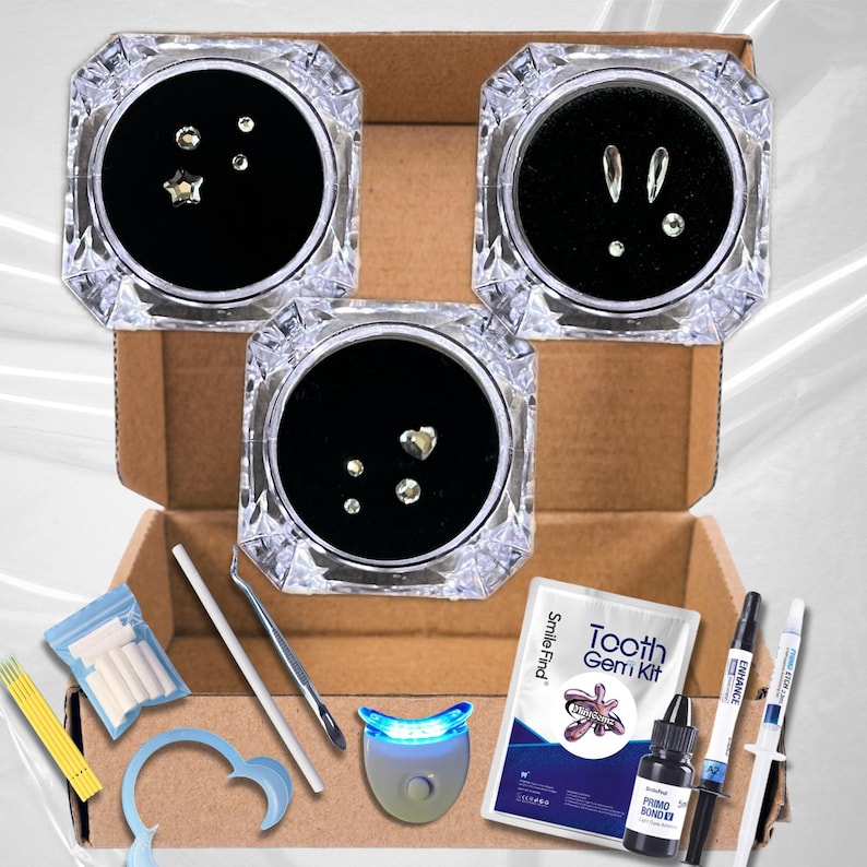 May include: A tooth gem kit with three containers of different sized gems, a blue light teeth whitening device, a bottle of bonding glue, a tube of dental cement, a small bag of tooth molds, a set of wooden sticks, a small tool, and a small blue mouth guard. The kit also includes a card with the text "Tooth Gem Kit" and "Smile Find".