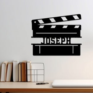 May include: Black metal wall decor shaped like a clapperboard with the name "JOSEPH" written on it.