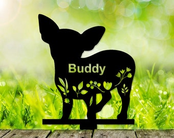 May include: Black metal silhouette of a chihuahua with the name "Buddy" on the body. The silhouette is set against a green grassy background.