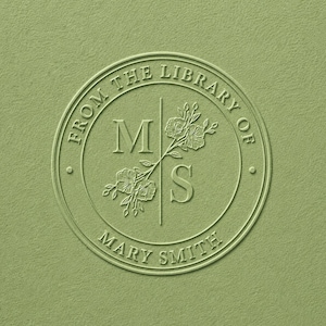 May include: A circular sage green embossed stamp design featuring the text FROM THE LIBRARY OF and MARY SMITH. The centre displays the letters M and S separated by a vertical line, with a floral illustration integrated between the letters.