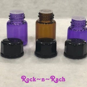 May include: Three small glass bottles with black caps. Two bottles are purple and one is brown.