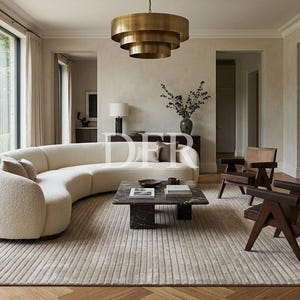 Op de afbeelding: Een woonkamer met een grote crèmekleurige gebogen bank, twee donkerhouten fauteuils met gevlochten rugleuningen en een rechthoekige salontafel van zwart marmer. Een getrapte koperen hanglamp hangt boven een getextureerd vloerkleed.