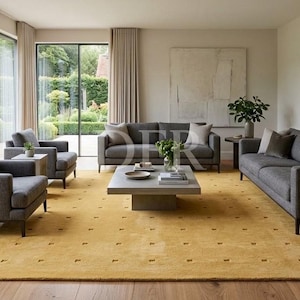 May include: A living room set featuring a large yellow area rug with a subtle grid pattern, two dark gray sofas, two matching armchairs, a low rectangular gray coffee table, and two gray side tables, all arranged on light wood flooring.