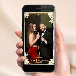 Może przedstawiać: Cyfrowa ramka do fotobudki z złotą ramką i białymi kwiatami. Ramka zawiera tekst "the wedding of Emily & James 08-24-2024". Para sta pozując do zdjęcia w ramce.