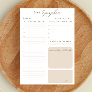 May include: A printable daily planner with a minimalist design. The planner includes sections for daily tasks, priorities, and water intake. The text "Mein Tagesplan" is at the top of the page.