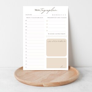 May include: A printable daily planner with a simple design. The planner includes sections for daily tasks, priorities, and water intake. The text on the planner reads "Mein Tagesplan", "Datum", "Mein Tagesablauf", "M D M D F S S", "Priorit&auml;t des Tages", "Wasser Getrunken", and "wofer ich heute lopbar ber".