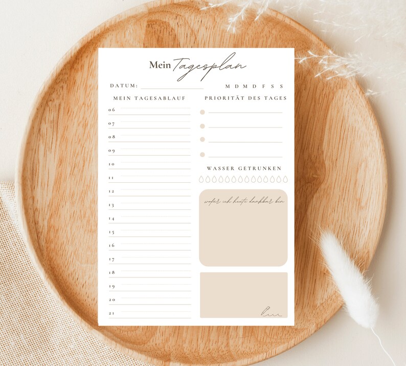 May include: A printable daily planner with a beige background. The planner has a section for daily tasks, a section for priorities, and a section for tracking water intake. The text on the planner reads "Mein Tagesplan", "DATUM", "MEIN TAGESABLAUF", "MDMDFSS", "PRIORITAT DES TAGES", and "WASSER GETRUNKEN".