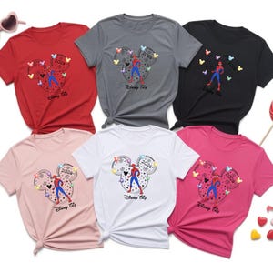 May include: Six t-shirts in red, grey, black, pink, white, and rose. Each shirt features a Mickey Mouse head design with a Spider-Man figure and the text "Disney Trip 2024".