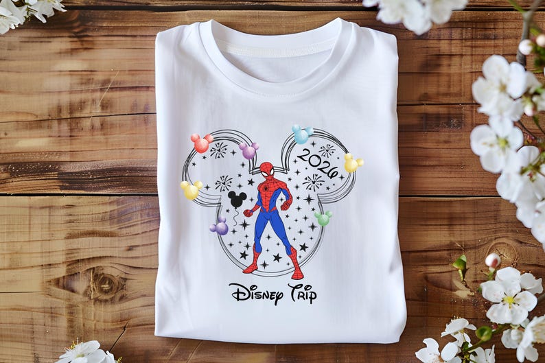 May include: White t-shirt with a graphic of Spider-Man within a Mickey Mouse head outline, with colourful balloons and the text "2026 Disney Trip". The design is in black, red, blue, and yellow.