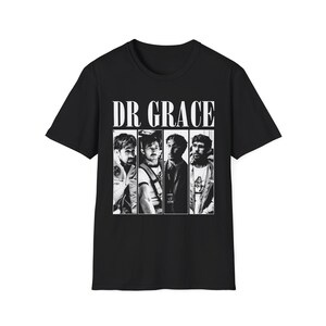 Puede incluir: Camiseta negra con el texto "DR GRACE" sobre una imagen en blanco y negro de cuatro personas. La imagen está dividida en cuatro secciones verticales, cada una mostrando una persona diferente. La camiseta es de material suave.