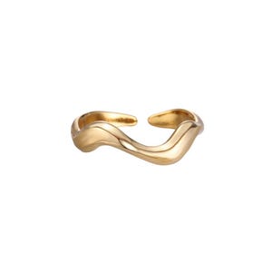 Könnte beinhalten: Ein goldfarbener Ring mit einem fließenden, organischen Design. Der Ring hat eine wellenförmige, offene Form mit einer Lücke oben. Das Metall hat eine glatte, polierte Oberfläche, die das Licht reflektiert. Das Design des Rings ist modern und minimalistisch.