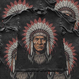 Op de afbeelding: Een antracietzwart t-shirt met korte mouwen en een grote, gecentreerde afbeelding van een persoon met een traditionele verentooi. De illustratie gebruikt tinten rood, wit en bruin, met een herhalend patroon van hetzelfde ontwerp.