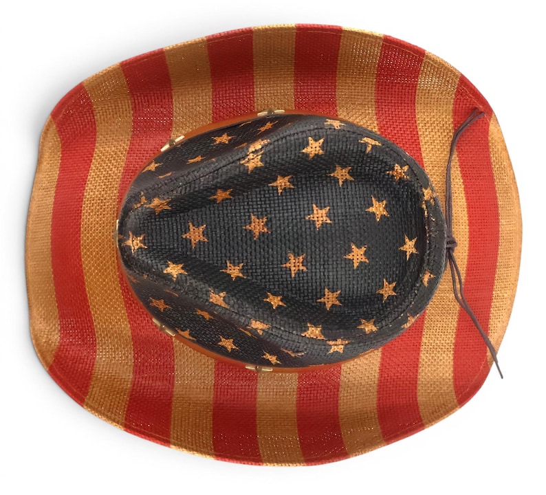 May include: Cowboy hat with a patriotic design. The hat features a black crown adorned with gold stars, and a brim with red and gold vertical stripes. A brown string is attached to the hat.