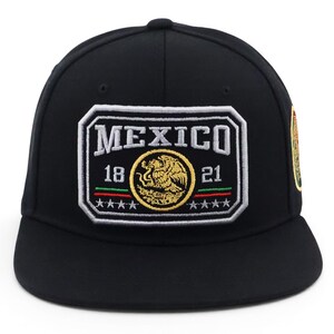 May include: Black baseball cap with a flat brim. The front features a rectangular patch with the word "MEXICO", the years "18" and "21", and a gold emblem. The patch is outlined in white with red, green, and gold accents.
