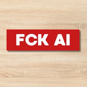 Op de afbeelding: Een rechthoekige sticker met een effen rode achtergrond en de witte tekst FCK AI gedrukt in een vet, schreefloos lettertype. De sticker heeft een strak, plat ontwerp met scherpe hoeken en toont de tekst duidelijk tegen de rode kleur.