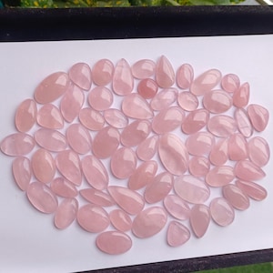 May include: A collection of pink rose quartz cabochons in various sizes and shapes. The cabochons are smooth and polished, with a translucent appearance.