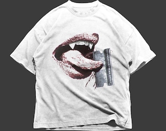 May include: White t-shirt with a graphic print of a red mouth with fangs and a tongue sticking out, holding a razor blade.