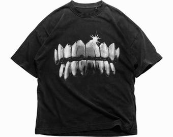 May include: Black t-shirt with a graphic of a set of silver teeth with a diamond on top.