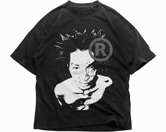 May include: Black t-shirt with a white graphic of a person's face, spiky hair, and a registered trademark symbol. The design is artistic and stylized. The shirt has a vintage, worn appearance.