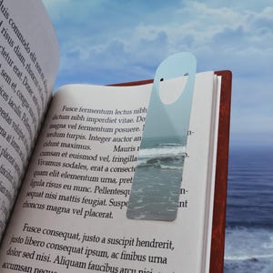 May include: A light blue bookmark with a wave design and a white smile. The bookmark is placed on an open book with text about a lectus nibh dictum.