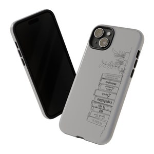 May include: A gray iPhone case with a black outline and a design of a stack of books with titles like "Fearless", "Red", "15 1949", "Reputation", "Lover", "Folklore", "Evermore", "Midnights", "The Tortured", and "Poets Demitment". A small plant is drawn on the top of the stack of books.