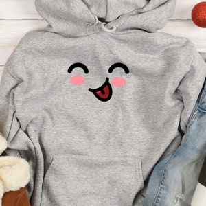 May include: A gray hoodie with a cartoon smiley face with a tongue sticking out. The face has pink cheeks and black eyes.
