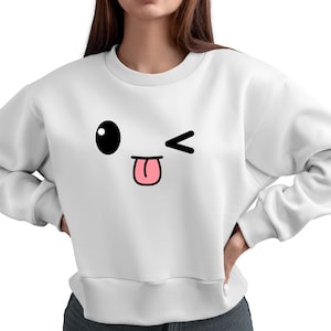 May include: White sweatshirt with a cartoon face printed on the front. The face has a large black eye, a pink tongue sticking out, and a winking eye.