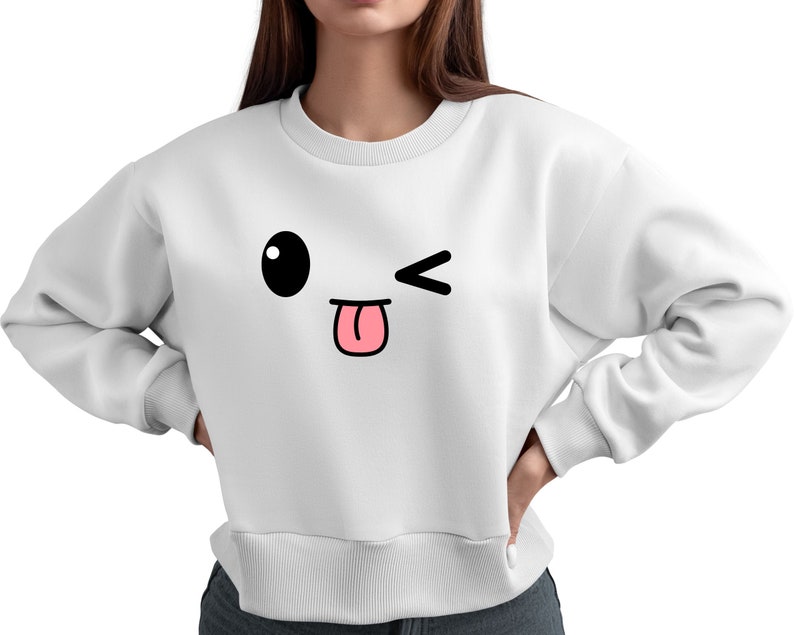 May include: White sweatshirt with a cartoon face printed on the front. The face has a large black eye, a pink tongue sticking out, and a winking eye.