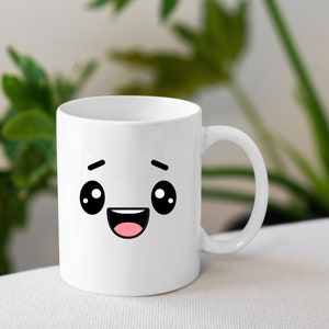 May include: White ceramic mug with a cartoon face with big eyes and a wide smile. The mug has a black outline and pink mouth.