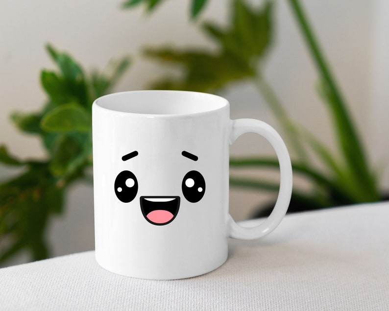 May include: White ceramic mug with a cartoon face with big eyes and a wide smile. The mug has a black outline and pink mouth.