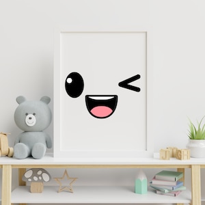 May include: A white framed print with a black and pink cartoon face with a winking eye and a wide smile. The print is hanging on a white wall above a wooden shelf with a teddy bear, a wooden toy, and books.