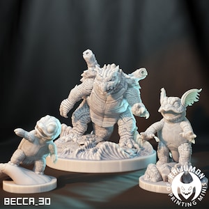 May include: Three 3D printed figurines of turtle-like creatures. The largest figurine is standing on a base with waves. The middle figurine is standing on a base with rocks. The smallest figurine is standing on a surfboard.