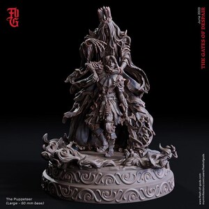 May include: A detailed, dark gray miniature sculpture titled "The Puppeteer" from "The Gates of Despair" collection. The sculpture features two figures, one towering over the other, on a decorative base. The base is 50 mm in diameter.