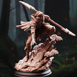 May include: A detailed figurine of a warrior in a dynamic pose, holding a spear with a double-edged blade. The figure is clad in a hooded cloak and stands atop a rocky base with miniature trees. The color is a warm, earthy tone.