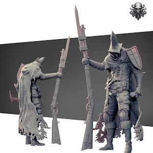 May include: A grey, hooded figure with a long, pointed hat holds a large, detailed spear. The figure is wearing a long, flowing cloak and has a shield on their left arm. The figure is standing on a grey background.