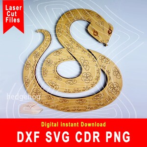 May include: A laser cut wooden snake design with a floral pattern. The snake is curled up in a circle with its head facing the right. The design is perfect for crafting projects.