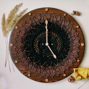 May include: A wooden clock with a brown and black crocheted design. The clock has wooden hands and a brown wooden frame.