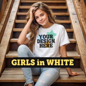 May include: A woman wearing a white t-shirt with the text "YOUR DESIGN HERE" and a green and yellow star. She is sitting on wooden stairs and wearing blue jeans.